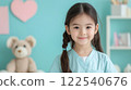 young girl in veterinarian scrubs smiles warmly in playful setting with teddy bear and heart decor 122540676