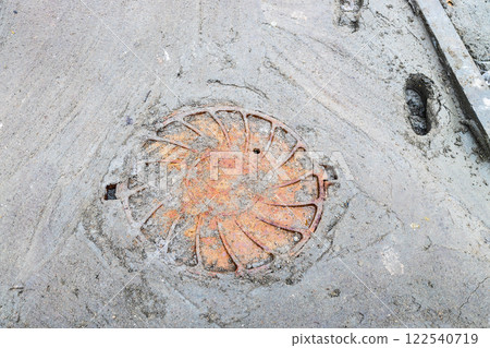 rusty sewer manhole cover on poorly concreted pat rusty sewer manhole cover on poorly concreted pat 122540719