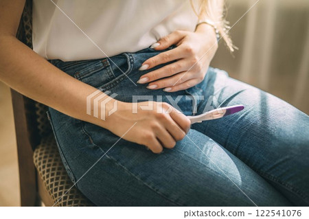 young woman holding a pregnancy test while sitting, a moment of anticipation, concept of family planning, healthcare, life changes 122541076