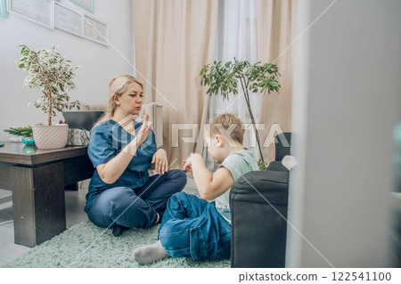 speech therapist engaging with young boy in nonverbal communication training, living room with warm decor, concept of education and cognitive skills development speech therapist engaging with young boy in nonverbal communication training, living room with warm decor, concept of education and cognitive skills development 122541100
