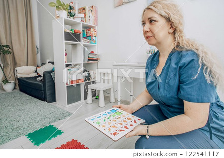 therapist in a blue uniform in bright modern classroom with learning materials and colorful puzzle board, concept of childhood education, speech therapy, cognitive development therapist in a blue uniform in bright modern classroom with learning materials and colorful puzzle board, concept of childhood education, speech therapy, cognitive development 122541117