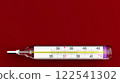 Glass mercury thermometer for measuring human body temperature. Red background. Medicine and health 122541302
