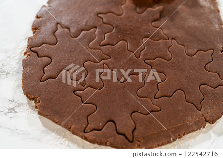 A close-up of snowflake-shaped cookie cutters pressed into Chocolate Ginger Sugar Cookie dough, capturing the intricate details of the shapes. A close-up of snowflake-shaped cookie cutters pressed into Chocolate Ginger Sugar Cookie dough, capturing the intricate details of the shapes. 122542716
