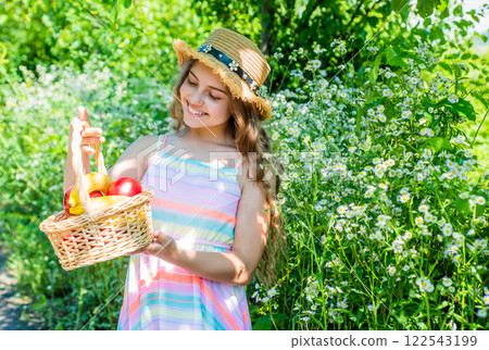 Happy small girl with fashion look in summer style hold harvest fruit basket on natural sunny lanscape in countryside, harvesting Happy small girl with fashion look in summer style hold harvest fruit basket on natural sunny lanscape in countryside, harvesting 122543199