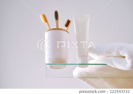 Toothbrush, toothpaste and bath accessories on a glass shelf in the bathroom. 122543532