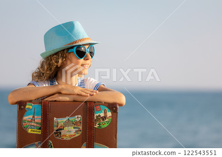 Happy child traveler with old suitcase. Summer vacation and travel concept Happy child traveler with old suitcase. Summer vacation and travel concept 122543551