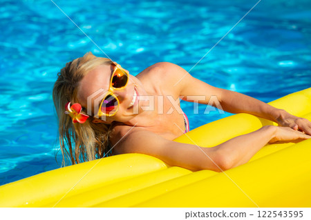 Happy young woman having fun in swimming pool on summer vacation 122543595