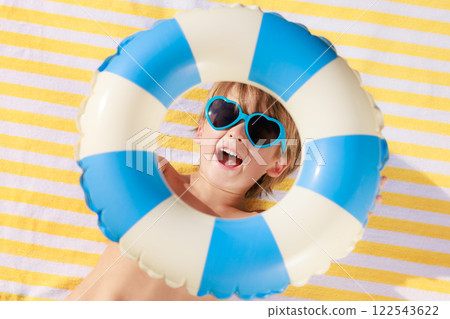 Top view portrait of happy child lying on beach towel on summer vacation Top view portrait of happy child lying on beach towel on summer vacation 122543622