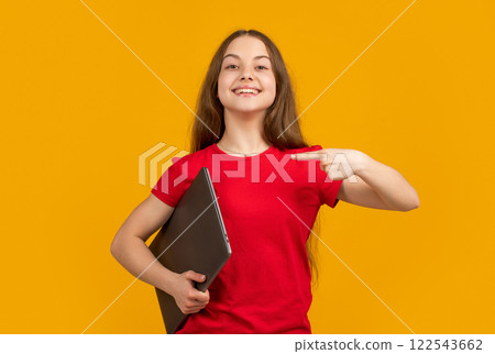 happy teen child point finger on laptop on yellow background 122543662