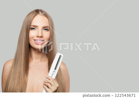 Joyful fashion model woman using hair straighteners iron on white background. Joyful fashion model woman using hair straighteners iron on white background. 122543671
