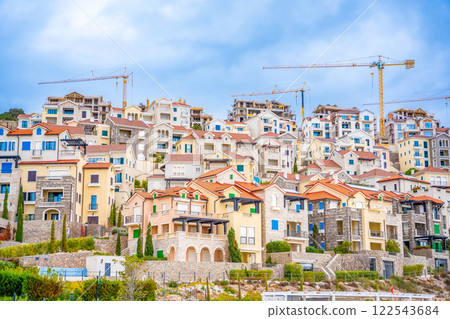 Construction site on the sea coast: view of tower cranes standing over tourist complex in Lustica bay, Montenegro. Construction site on the sea coast: view of tower cranes standing over tourist complex in Lustica bay, Montenegro. 122543684