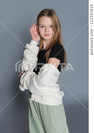 Young girl stands with arms crossed, her solemn face evoking thought. A reflection of the introspective moments in youth. 122543814