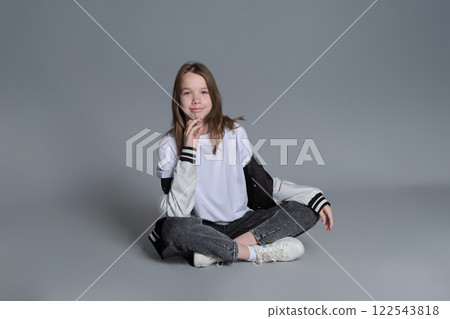 A girl in a casual outfit sits cross-legged, lost in thought. This image highlights the blend of innocence and emerging maturity, symbolizing the journey of self-discovery and individuality. A girl in a casual outfit sits cross-legged, lost in thought. This image highlights the blend of innocence and emerging maturity, symbolizing the journey of self-discovery and individuality. 122543818