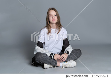 A girl in a casual outfit sits cross-legged, lost in thought. This image highlights the blend of innocence and emerging maturity, symbolizing the journey of self-discovery and individuality. A girl in a casual outfit sits cross-legged, lost in thought. This image highlights the blend of innocence and emerging maturity, symbolizing the journey of self-discovery and individuality. 122543821