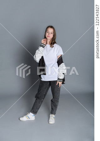 A teenage girl gazes downward, gently holding her jacket in a casual pose. Her expression hints at introspection, symbolizing the reflective nature of today s youth. A teenage girl gazes downward, gently holding her jacket in a casual pose. Her expression hints at introspection, symbolizing the reflective nature of today s youth. 122543827