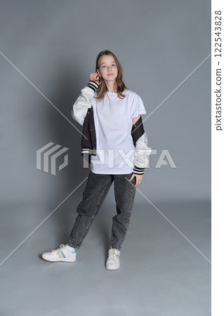 A girl stands in a relaxed pose with her jacket over her shoulders, gazing down. This image embodies the calm confidence of adolescence and the journey toward self-discovery. A girl stands in a relaxed pose with her jacket over her shoulders, gazing down. This image embodies the calm confidence of adolescence and the journey toward self-discovery. 122543828