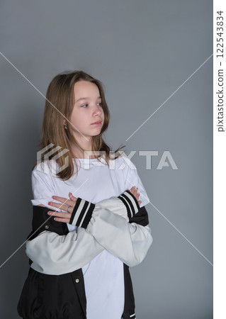 A girl turns slightly, looking thoughtfully to the side, her jacket resting on her shoulder. This portrait expresses the blend of innocence and emerging maturity seen in adolescence. A girl turns slightly, looking thoughtfully to the side, her jacket resting on her shoulder. This portrait expresses the blend of innocence and emerging maturity seen in adolescence. 122543834