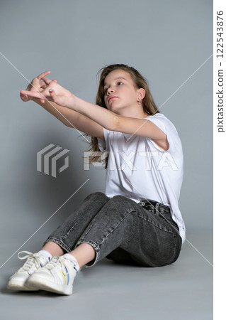 A young girl in a white t-shirt and jeans poses in a relaxed manner. The image captures the casual, laid-back style of today s youth, focusing on individuality and self-expression. A young girl in a white t-shirt and jeans poses in a relaxed manner. The image captures the casual, laid-back style of today s youth, focusing on individuality and self-expression. 122543876