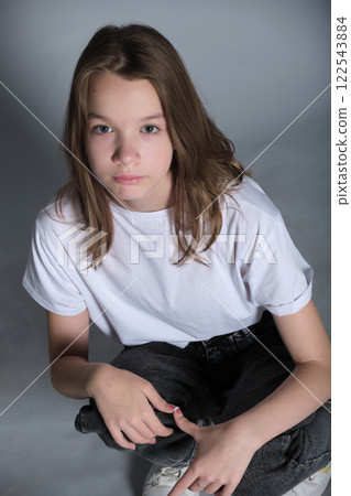 A young girl sits calmly while looking directly into the camera, wearing casual clothes. This portrait captures the sincerity and simplicity of modern youth photography. A young girl sits calmly while looking directly into the camera, wearing casual clothes. This portrait captures the sincerity and simplicity of modern youth photography. 122543884