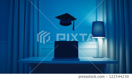 Graduation cap hovering over laptop in minimalist study room with moody lighting 122544230