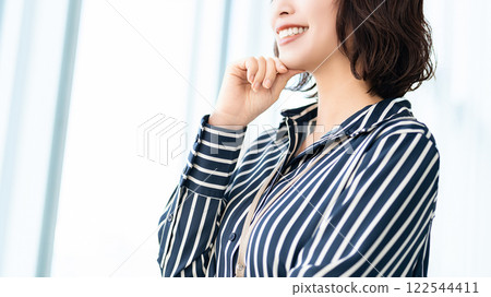 Smiling woman/businesswoman looking out the window Smiling woman/businesswoman looking out the window 122544411