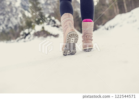 Active woman walking away from the camera through winter snow Active woman walking away from the camera through winter snow 122544571