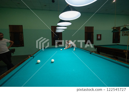 A group of people gathered in the billiard room to play and have fun. A group of friends plays billiards. People relax and play billiards. 122545727