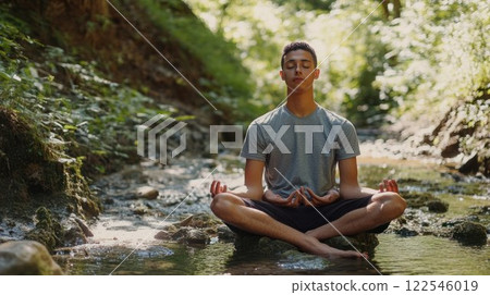 Young man meditating in a serene natural setting. 122546019