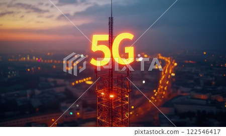 Illuminated 5G sign atop a telecommunications tower at sunset over a cityscape. 122546417