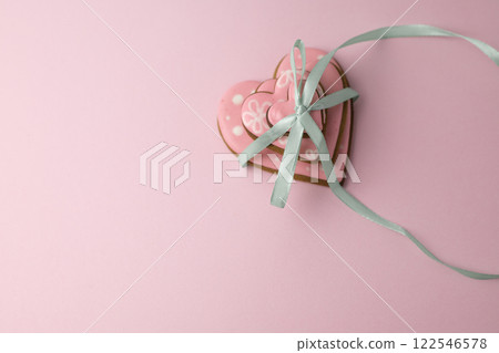 heart cookies with pink glaze of different sizes tied with a thin ribbon, creative baking concept for Valentine's Day 122546578