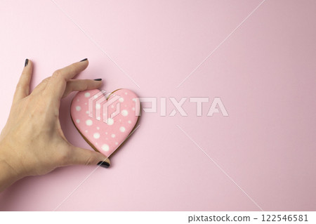 female hand holding cookies in the shape of hearts with pink icing, creative baking concept for Valentine's Day 122546581