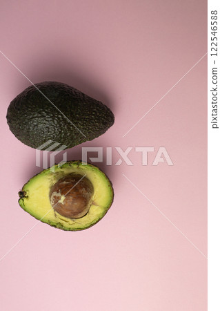 two halves of avocado on pink background 122546588