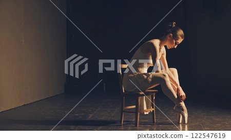 Backstage ballerina preparing pointe shoes on a chair 122547619