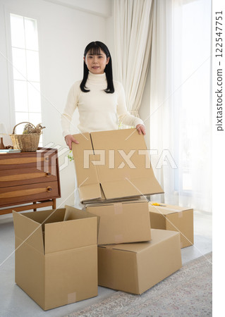 A woman breaking down cardboard boxes and tidying up A woman breaking down cardboard boxes and tidying up 122547751