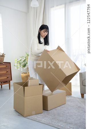 A woman breaking down cardboard boxes and tidying up 122547764