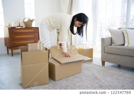 一名婦女正在拆開紙箱並進行整理 一名婦女正在拆開紙箱並進行整理 122547769