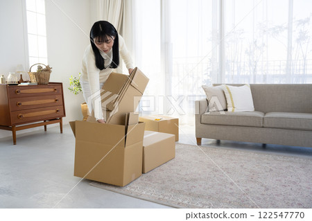 A woman breaking down cardboard boxes and tidying up A woman breaking down cardboard boxes and tidying up 122547770