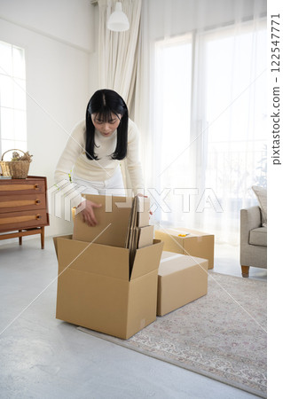 一名婦女正在拆開紙箱並進行整理 一名婦女正在拆開紙箱並進行整理 122547771