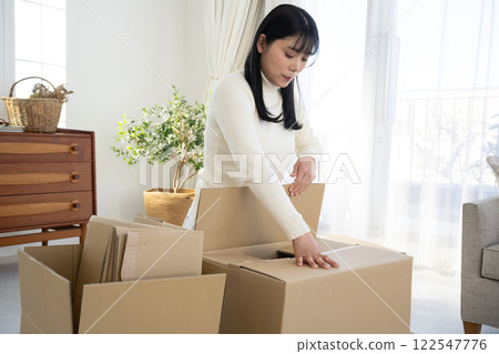 A woman breaking down cardboard boxes and tidying up 122547776