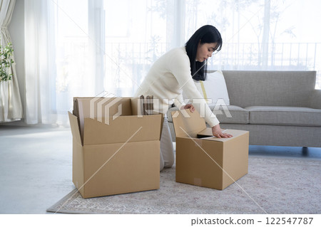 A woman breaking down cardboard boxes and tidying up A woman breaking down cardboard boxes and tidying up 122547787