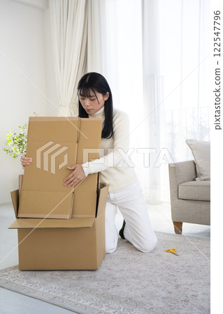 一名婦女正在拆開紙箱並進行整理 一名婦女正在拆開紙箱並進行整理 122547796