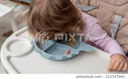 A playful toddler exploring food in a creative and funny way during mealtime. A playful toddler exploring food in a creative and funny way during mealtime. 122547941