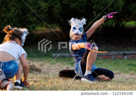Cute young little kid girl wear cat furry mask enjoy have fun playing outdoors in forest street park. Children therian wild animal character trendy fan culture. Teenager social expression hobby 122548100