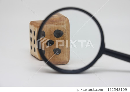 Dice through a magnifying glass, profit and revenue unpredictability, plan a marketing strategy. Dice through a magnifying glass, profit and revenue unpredictability, plan a marketing strategy. 122548109