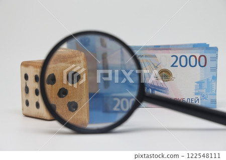 Dice and banknotes through a magnifying glass, profi Dice and banknotes through a magnifying glass, profi 122548111