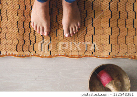 Yoga woman legs standing on nails with singing meditation bowl top view closeup 122548391