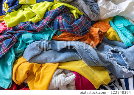 Pile of unfolded dirty clothes for laundry on the chair. Heap of used clothes for donation 122548394