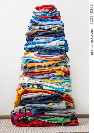 A very tall stack of folded colored clothes for charity, washing, ironing and sorting. 122548398