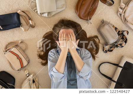 A young woman puts various women's handbags for storage in her home wardrobe. Accessories and bags. A young woman puts various women's handbags for storage in her home wardrobe. Accessories and bags. 122548427
