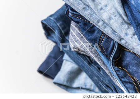 Stack of various shades of blue jeans on white background Stack of various shades of blue jeans on white background 122548428